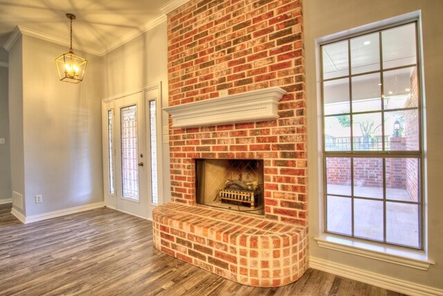 unfurnished living room with hardwood / wood-style floors, crown molding, a wealth of natural light, and a brick fireplace