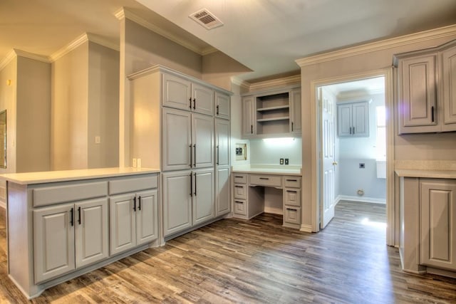 kitchen featuring hardwood / wood-style flooring, gray cabinetry, ornamental molding, and kitchen peninsula