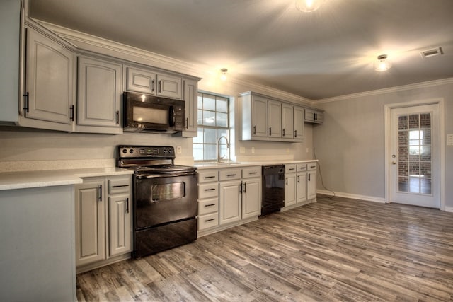 kitchen featuring crown molding, a wealth of natural light, hardwood / wood-style floors, and black appliances