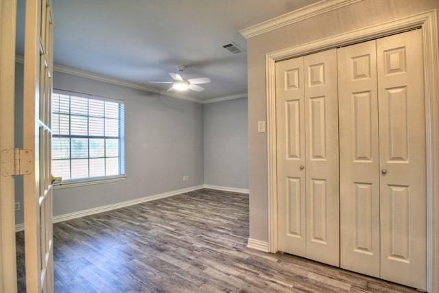 unfurnished bedroom featuring wood-type flooring, a closet, ceiling fan, and ornamental molding