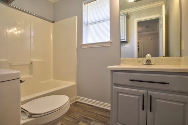 full bathroom with ornamental molding,  shower combination, vanity, hardwood / wood-style flooring, and toilet