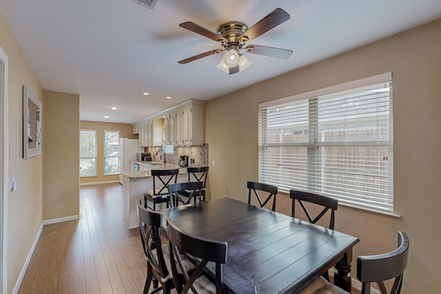 dining area with ceiling fan, light hardwood / wood-style flooring, and sink