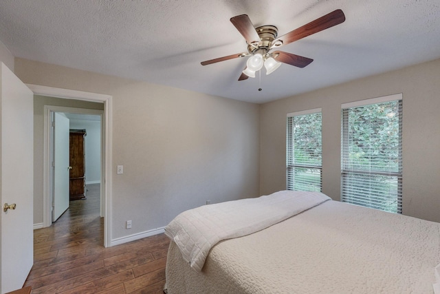 bedroom featuring a textured ceiling, ceiling fan, and dark wood-type flooring