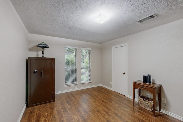 unfurnished room featuring a textured ceiling and dark hardwood / wood-style floors