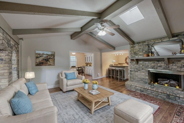 living room with a fireplace, wood-type flooring, lofted ceiling with skylight, and ceiling fan