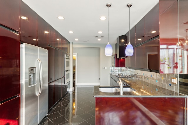 kitchen with decorative light fixtures, dark stone counters, dark tile patterned floors, stainless steel appliances, and decorative backsplash