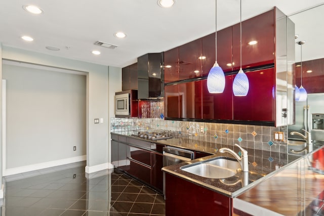 kitchen with sink, tasteful backsplash, appliances with stainless steel finishes, pendant lighting, and wall chimney range hood