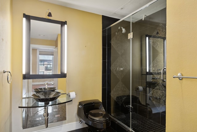 bathroom featuring toilet, sink, and a shower with shower door