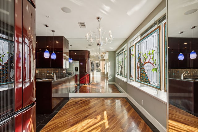 interior space with dark hardwood / wood-style flooring, hanging light fixtures, a notable chandelier, and backsplash