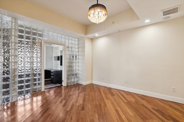 unfurnished living room with hardwood / wood-style flooring, a chandelier, and a tray ceiling