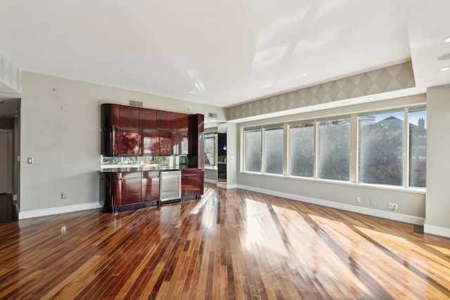 unfurnished living room featuring wood-type flooring and beverage cooler