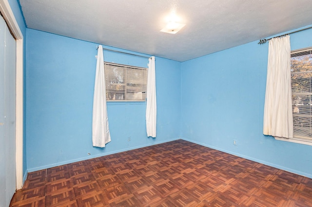 spare room with dark parquet flooring and a textured ceiling