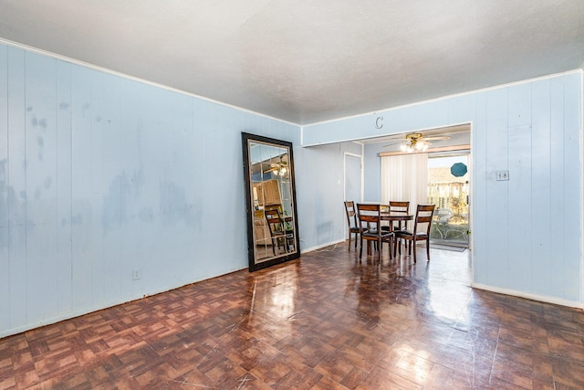 dining area featuring dark parquet floors, wood walls, and a textured ceiling