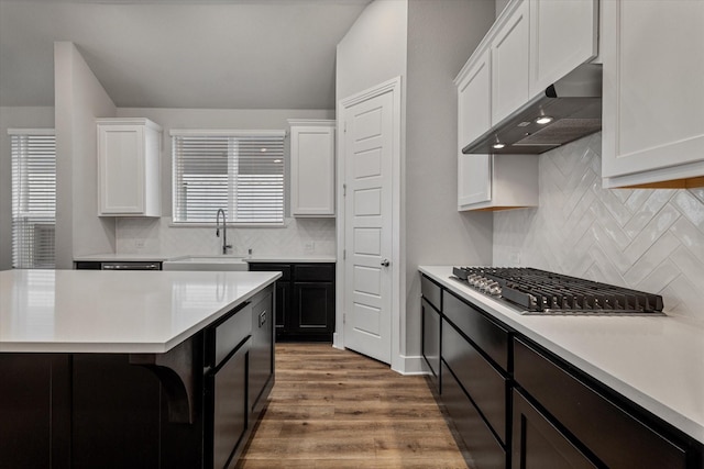 kitchen featuring dark wood-type flooring, white cabinetry, wall chimney exhaust hood, and sink