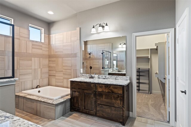 full bath with a garden tub, two vanities, a tile shower, and a sink