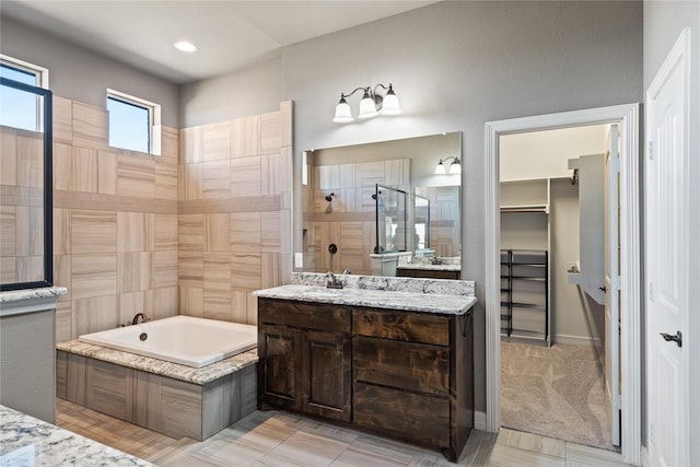 full bath with vanity, a spacious closet, a bath, and a tile shower