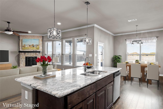 kitchen featuring a sink, dark brown cabinetry, ornamental molding, a fireplace, and stainless steel dishwasher