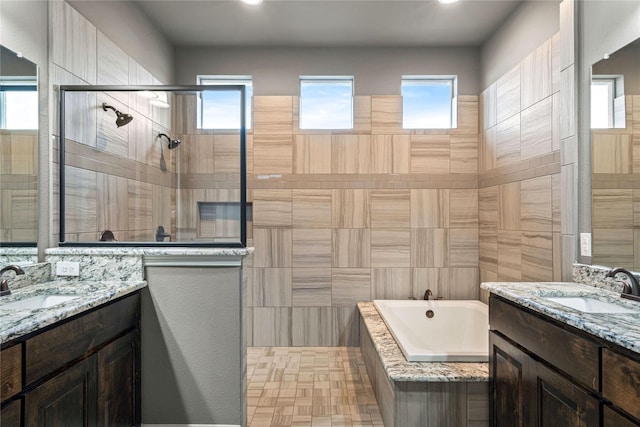 full bathroom featuring a sink, two vanities, a bath, and a tile shower