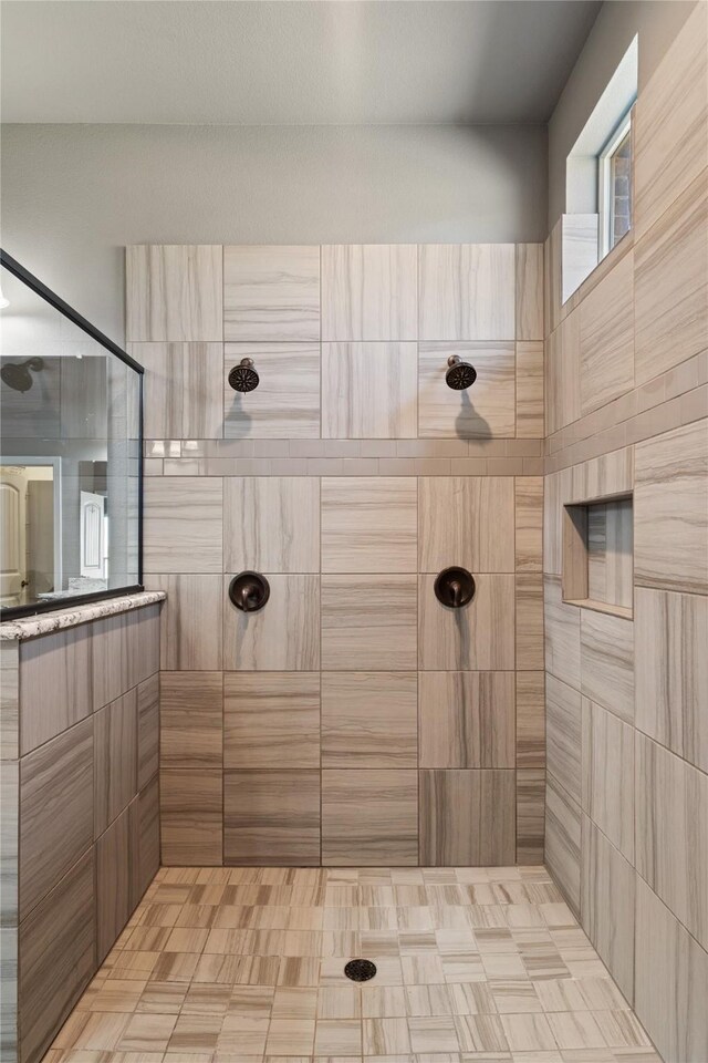 full bath featuring baseboards, tiled shower, a ceiling fan, and vanity