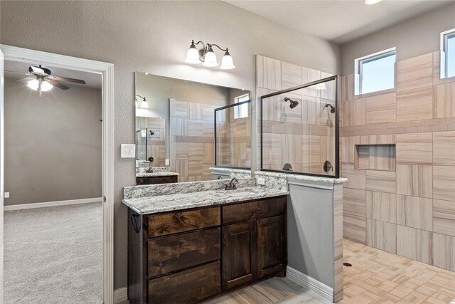 bathroom with baseboards, tiled shower, vanity, and a ceiling fan