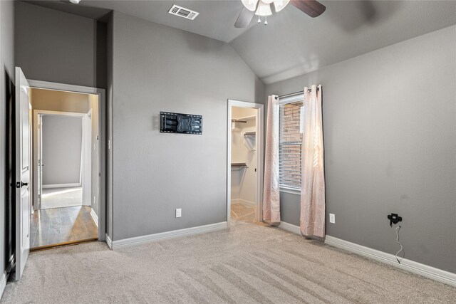 empty room featuring carpet flooring, a ceiling fan, baseboards, and vaulted ceiling