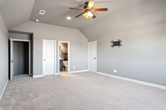 unfurnished bedroom featuring visible vents, baseboards, lofted ceiling, light carpet, and ensuite bathroom
