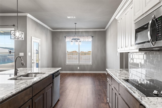 kitchen with baseboards, a sink, dark wood-type flooring, appliances with stainless steel finishes, and a notable chandelier