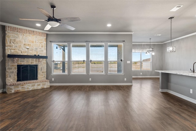 unfurnished living room featuring ceiling fan, dark hardwood / wood-style flooring, a fireplace, and crown molding