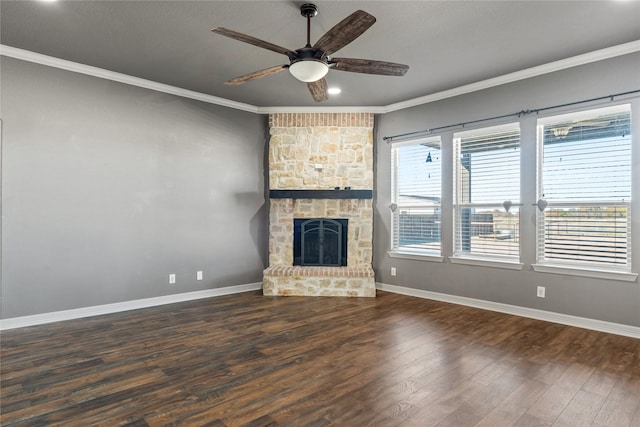 unfurnished living room featuring ceiling fan, a stone fireplace, crown molding, and dark wood-type flooring