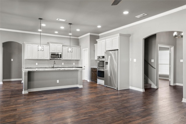 kitchen featuring appliances with stainless steel finishes, dark hardwood / wood-style flooring, pendant lighting, white cabinetry, and an island with sink