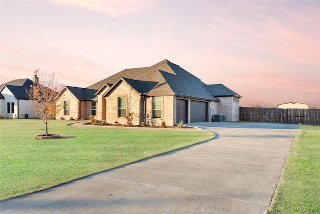 view of front facade featuring fence, driveway, a yard, a garage, and brick siding