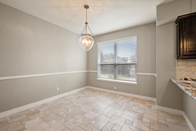 unfurnished dining area featuring a notable chandelier