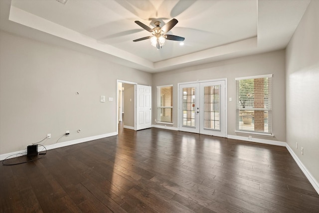 empty room featuring a raised ceiling, ceiling fan, french doors, and dark hardwood / wood-style floors