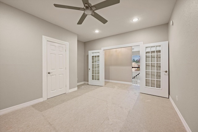 spare room featuring french doors, light colored carpet, and ceiling fan