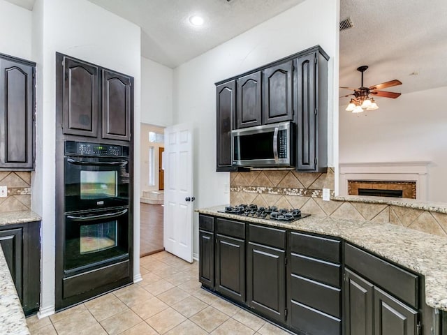 kitchen featuring light stone counters, light tile patterned floors, and black appliances