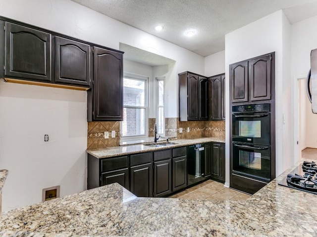 kitchen with black appliances, backsplash, light stone countertops, and sink