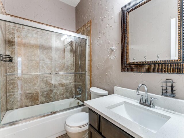 full bathroom with vanity, bath / shower combo with glass door, and toilet