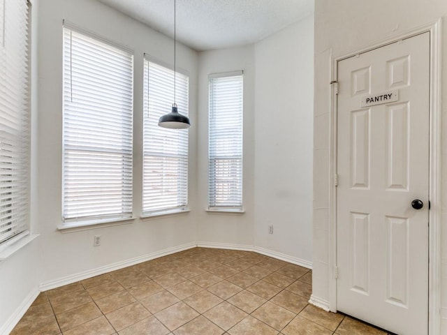 unfurnished dining area featuring plenty of natural light, light tile patterned floors, and a textured ceiling