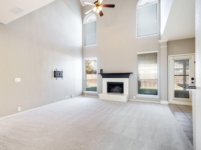 unfurnished living room with light carpet, a high ceiling, and ceiling fan