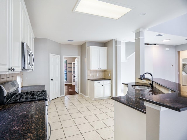 kitchen with kitchen peninsula, black gas range, white cabinetry, and sink