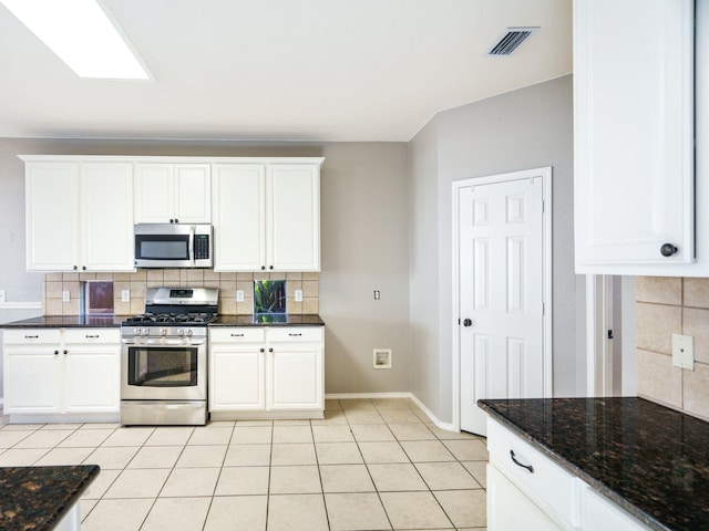 kitchen featuring tasteful backsplash, white cabinetry, light tile patterned floors, and appliances with stainless steel finishes