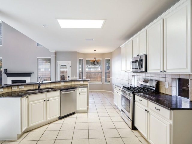 kitchen featuring appliances with stainless steel finishes, an inviting chandelier, white cabinetry, and sink