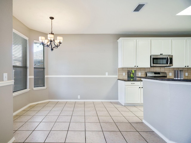 kitchen featuring decorative backsplash, an inviting chandelier, stainless steel appliances, and white cabinetry