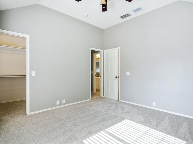 unfurnished bedroom featuring vaulted ceiling, ceiling fan, a spacious closet, light colored carpet, and a closet