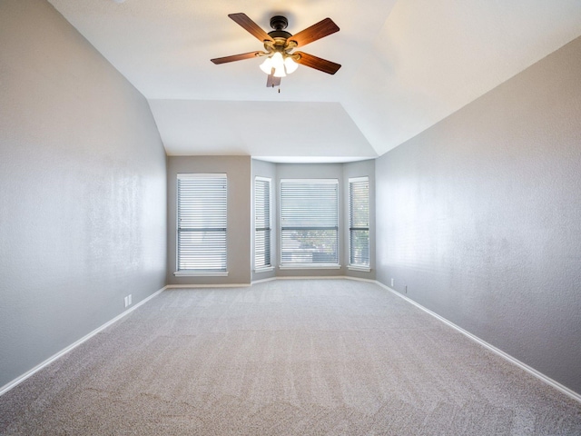 carpeted spare room with ceiling fan and vaulted ceiling