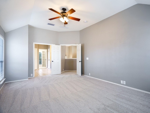 unfurnished bedroom featuring multiple windows, light colored carpet, vaulted ceiling, and ceiling fan