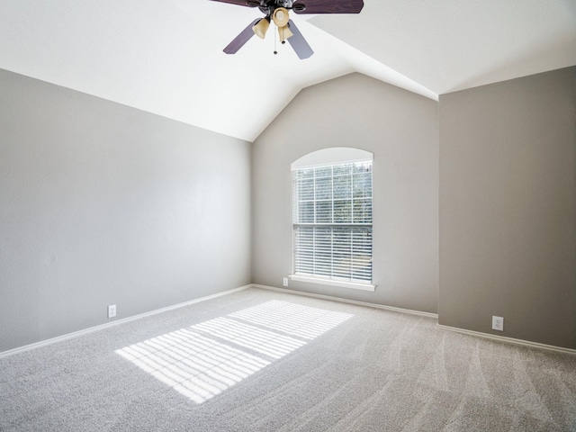 carpeted spare room with ceiling fan and vaulted ceiling