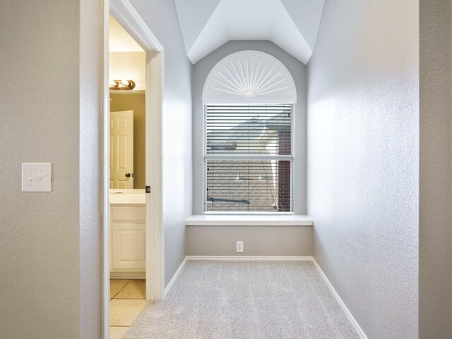 hall with light colored carpet and vaulted ceiling