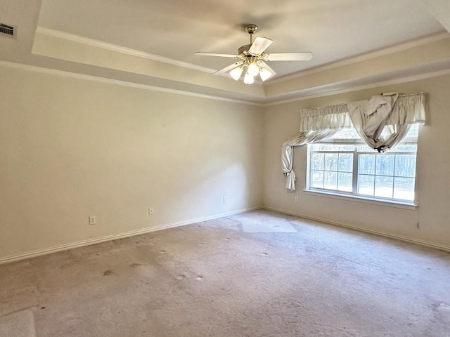 empty room with a tray ceiling, crown molding, and carpet floors