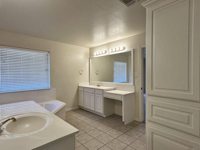 bathroom featuring tile patterned flooring, vanity, a tub to relax in, and a textured ceiling